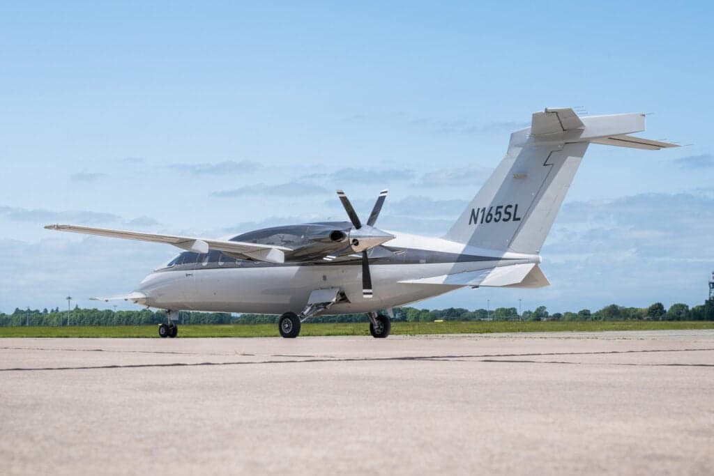 Rear side view of a Piaggio Avanti EVO aircraft with tail number N165SL on the tarmac.