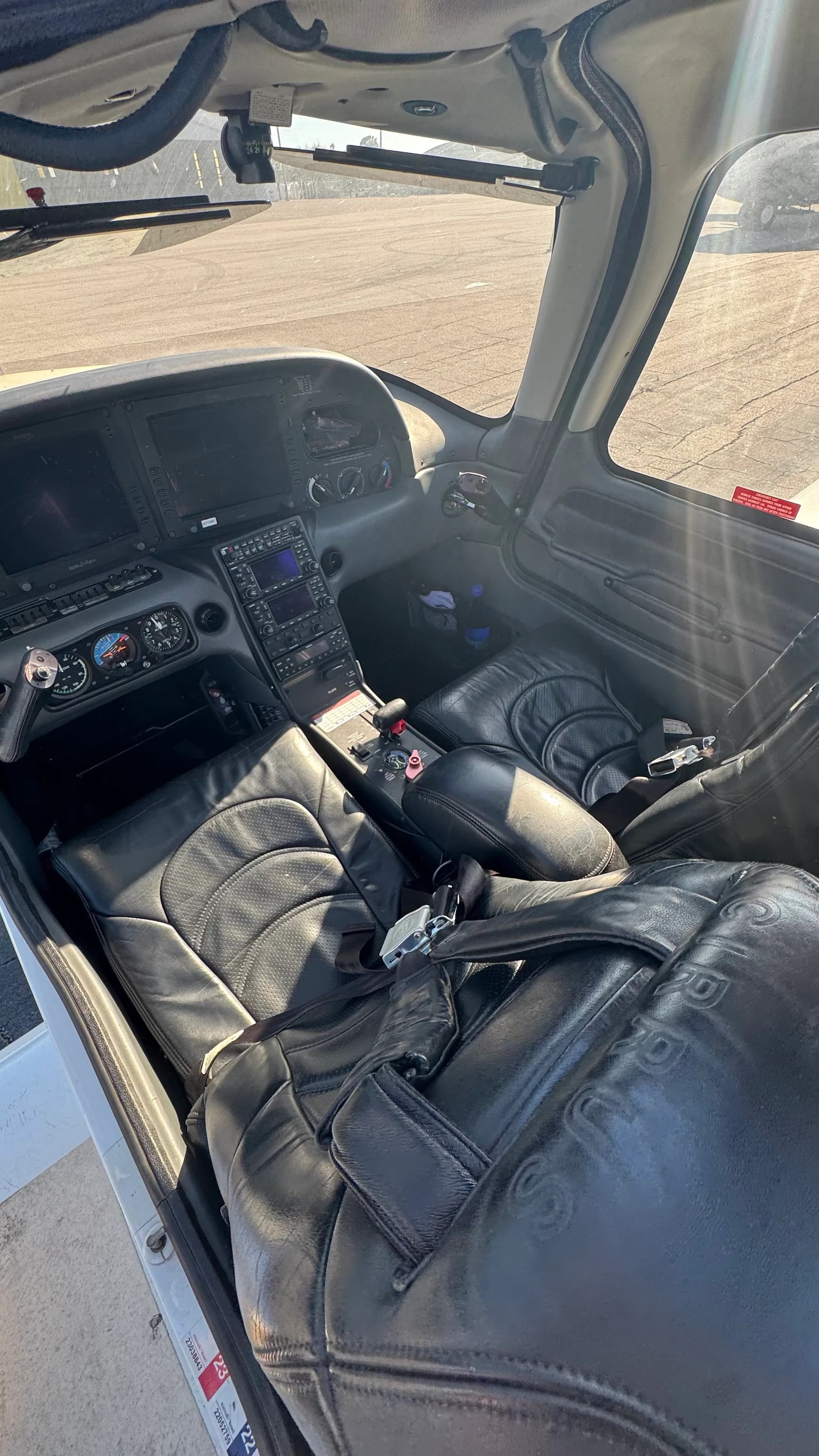 A sunlit view of the Cirrus SR22T cockpit, highlighting the black leather seats and instrument panel.