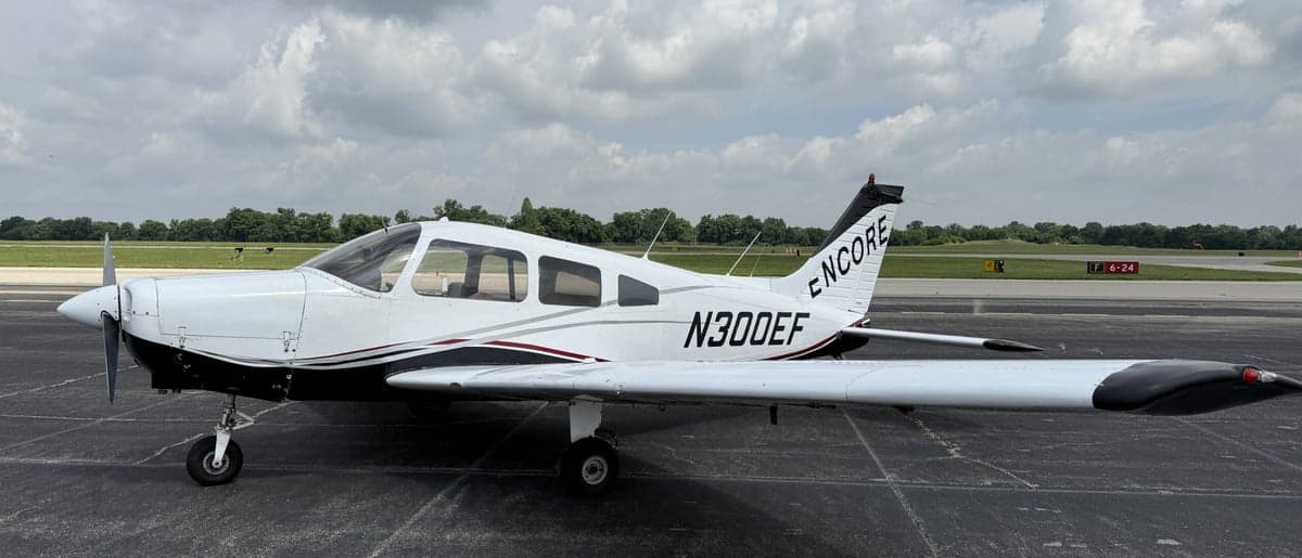 Side view of a white and black Piper PA-28-181 Archer II with registration N300EF on the tarmac.