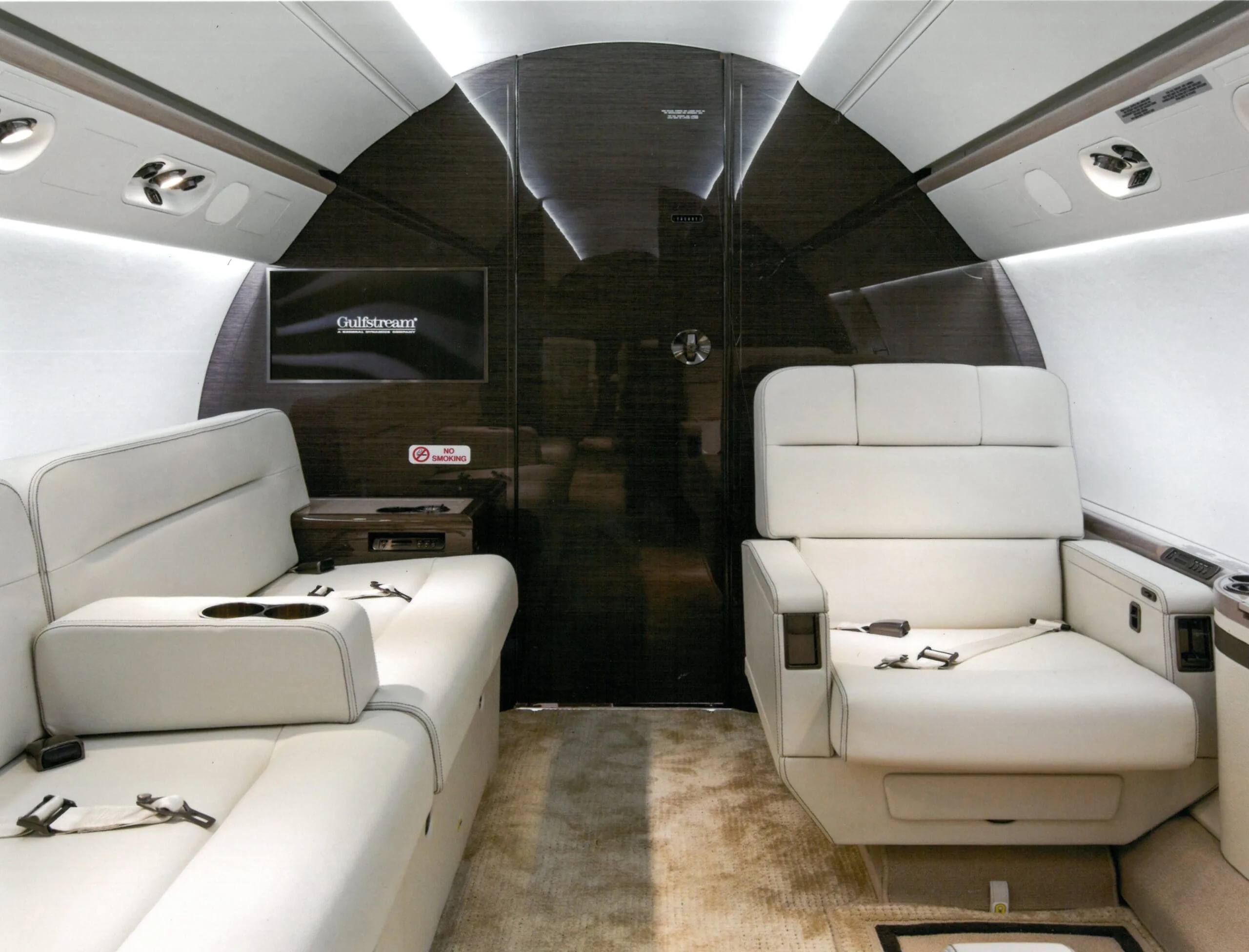 View of the aircraft cabin with white leather seats and a Gulfstream TV screen.