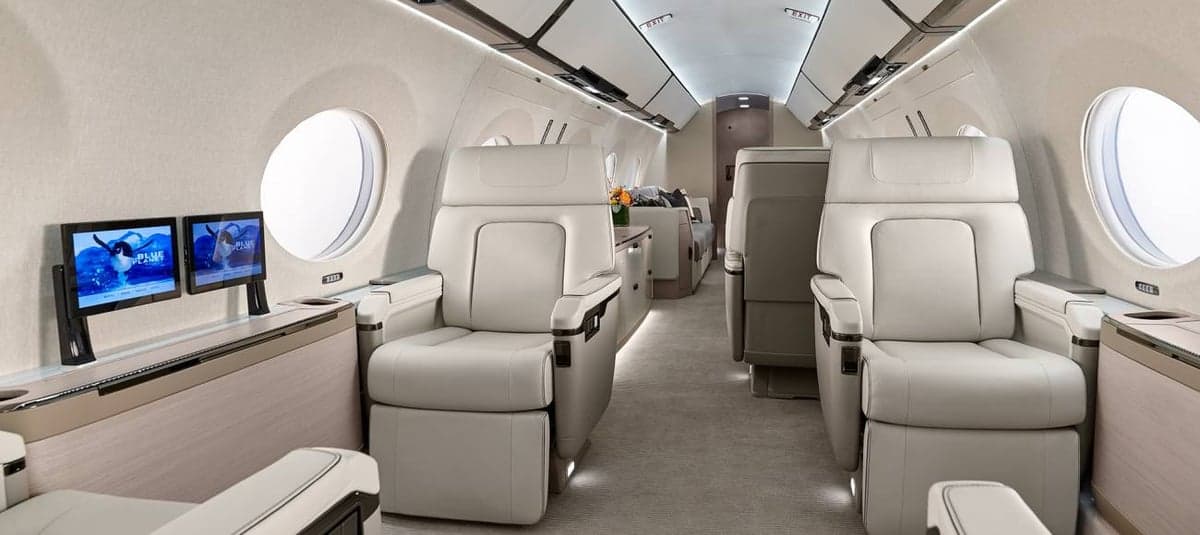 A view of the interior cabin of a private jet with cream-colored leather seats.