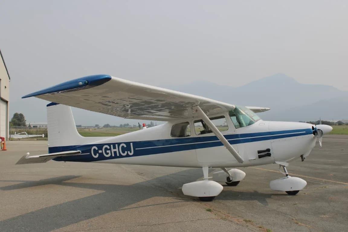Side view of a Cessna 172 with blue stripe parked on the tarmac.