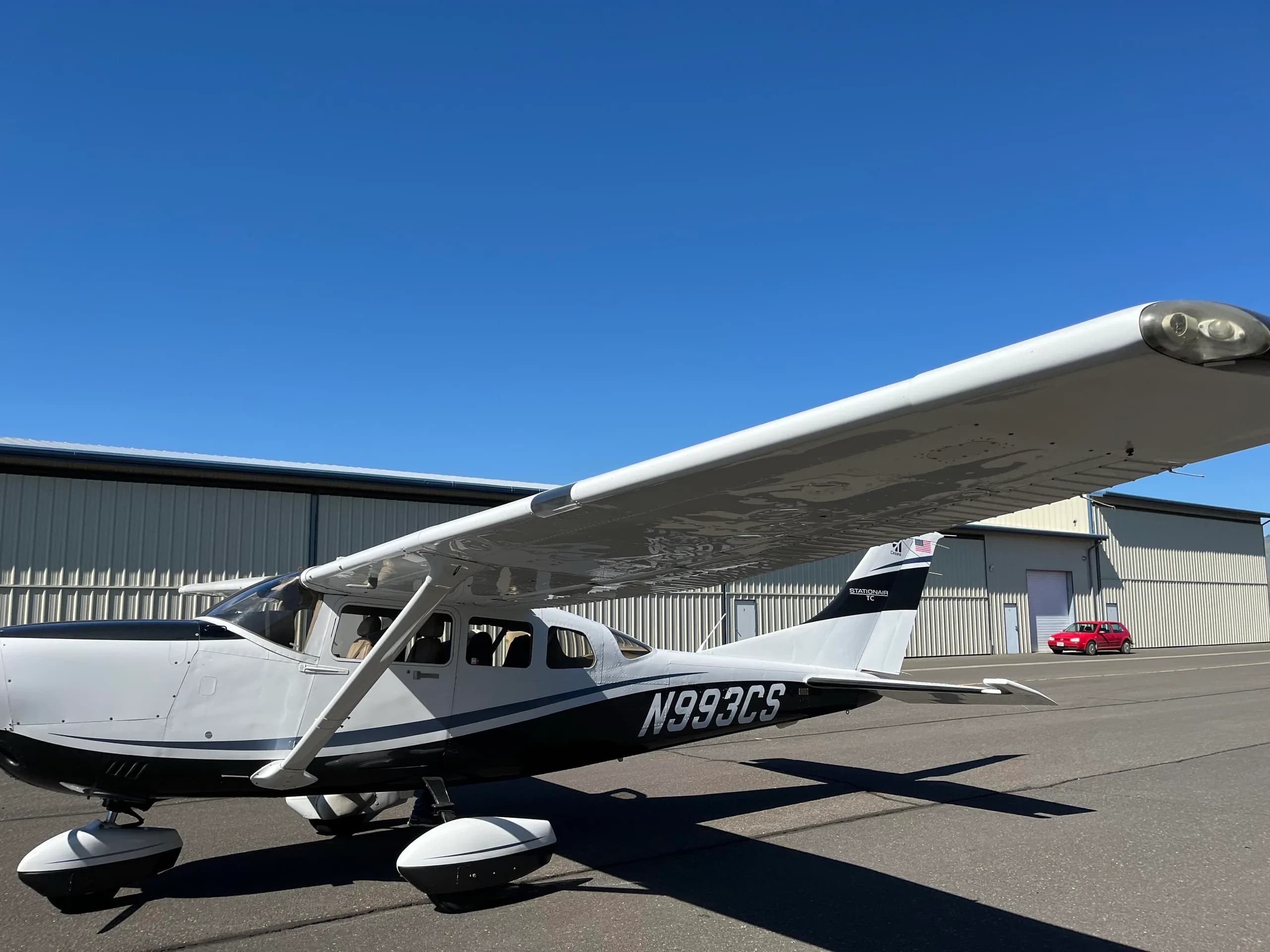 Cessna Stationair N993CS parked on the tarmac in front of a hangar.