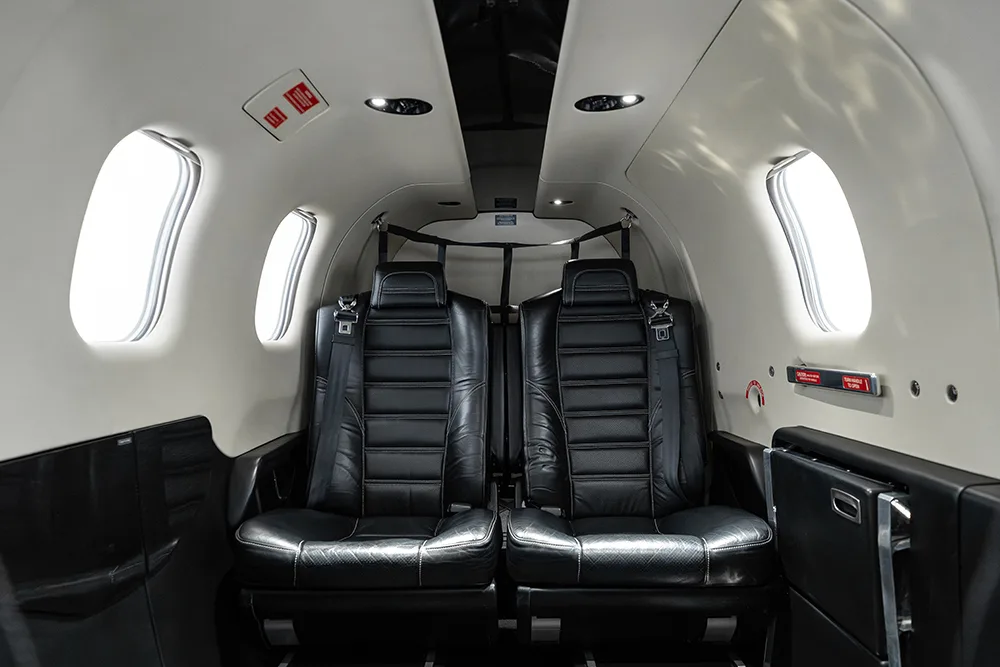 Interior view of the aircraft's rear cabin with two black leather seats and windows.