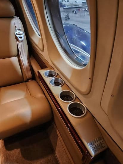 Interior view of the aircraft cabin with tan leather seats and cup holders.
