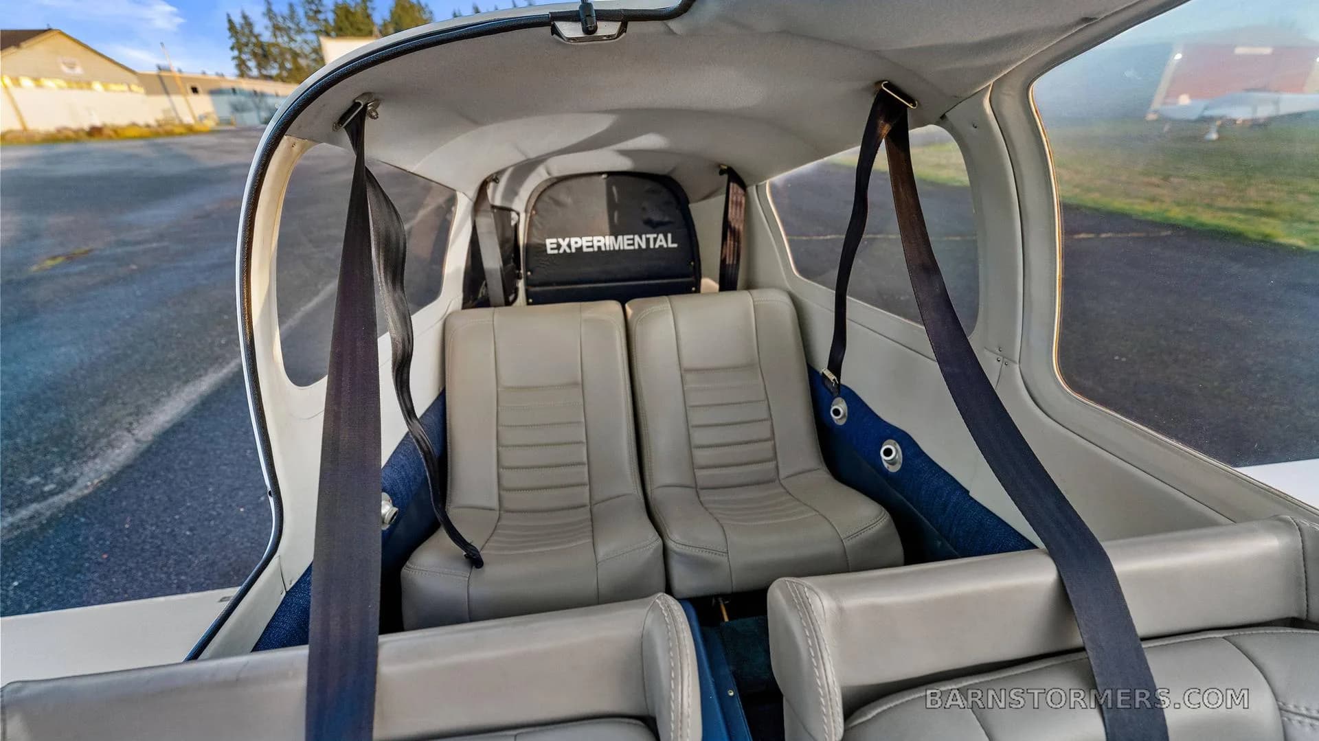 The light gray interior cabin of the aircraft, showing two rear seats with "EXPERIMENTAL" visible on a bag in the back.