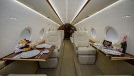 Interior view of the aircraft cabin with two white leather seats.