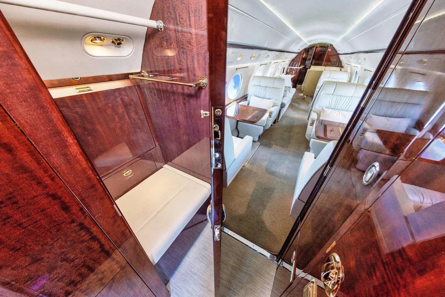 A view into a closet or storage area within the aircraft cabin, with a glimpse of the main seating area.