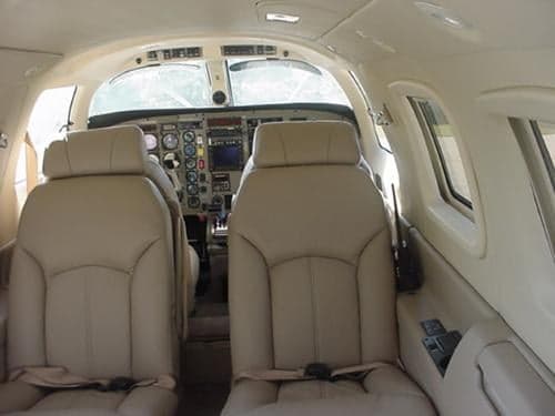 The interior of the aircraft features cream-colored leather seats and a view of the cockpit.