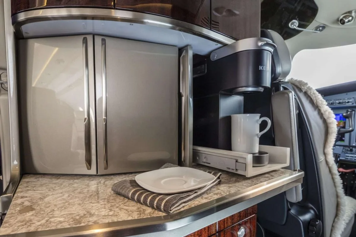 Interior view of the aircraft galley with a coffee maker and storage cabinets.