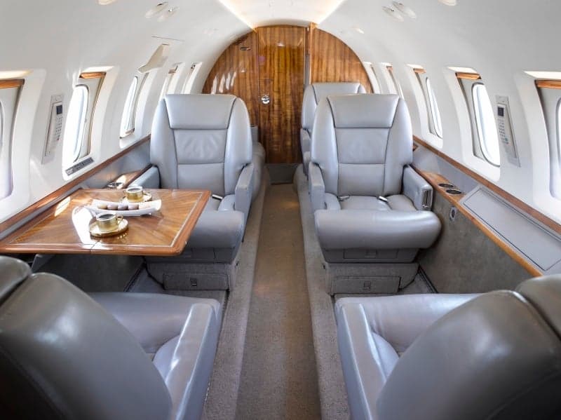 View of the aircraft interior with leather seats and wooden table.