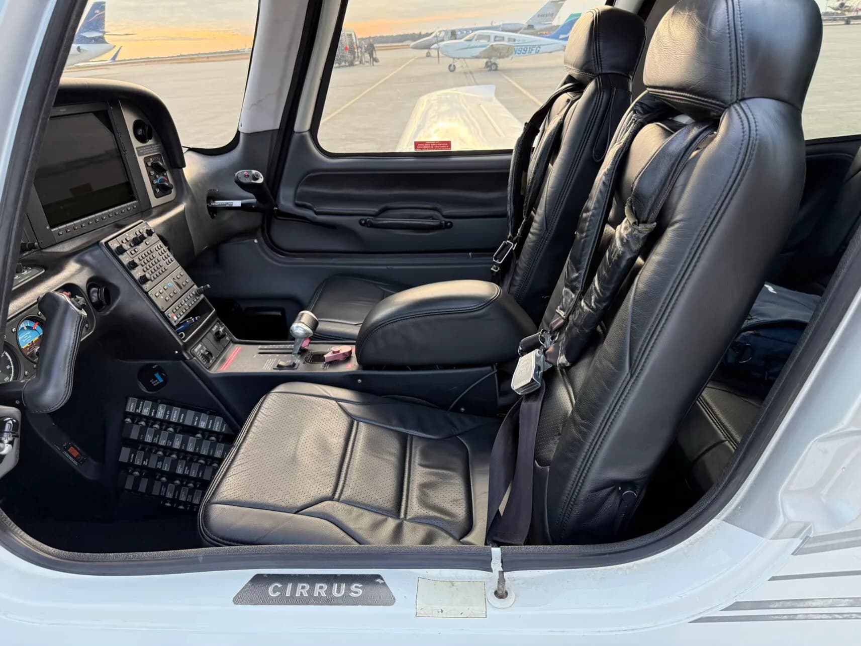 The front two black leather seats and partial cockpit view of a Cirrus SR22 aircraft.