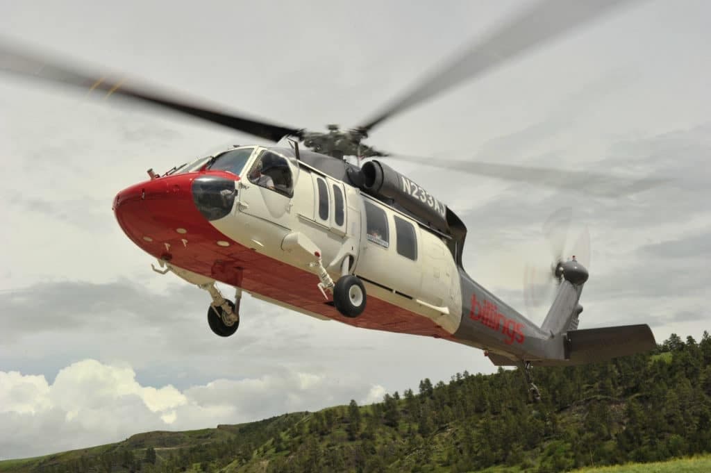 A white and red Sikorsky S-70i Firehawk helicopter in flight.
