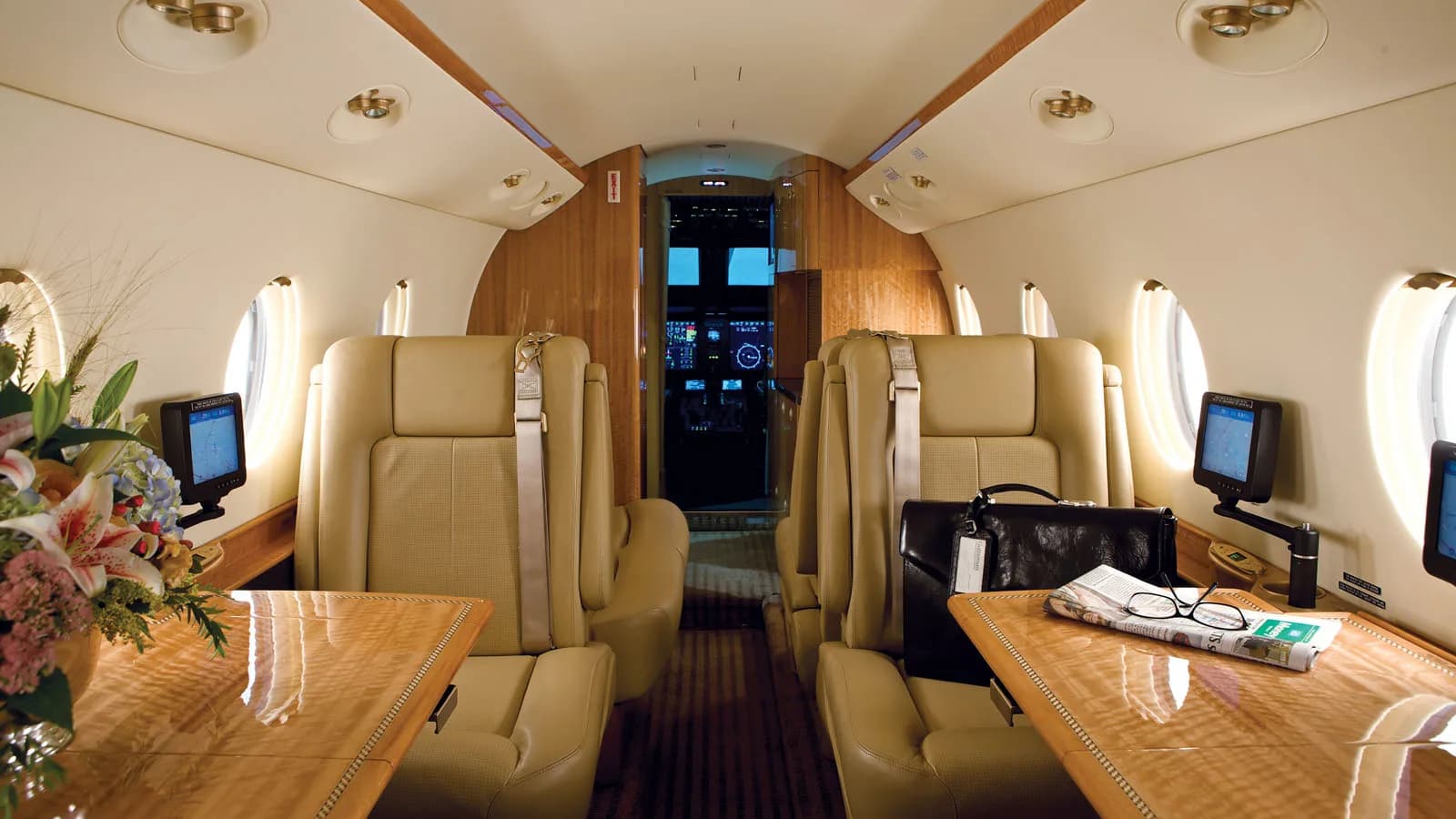 Interior view of the aircraft cabin with leather seats and tables.