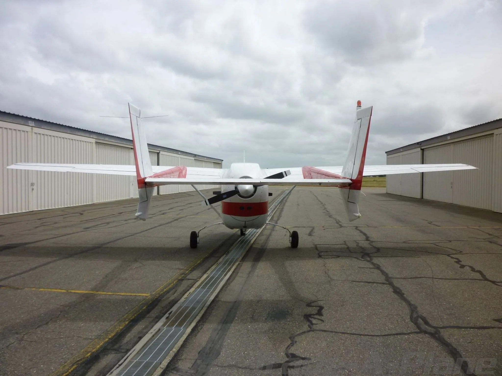 A rear view of the white and red Cessna Skymaster N2PJ with its twin tail booms and propeller visible.