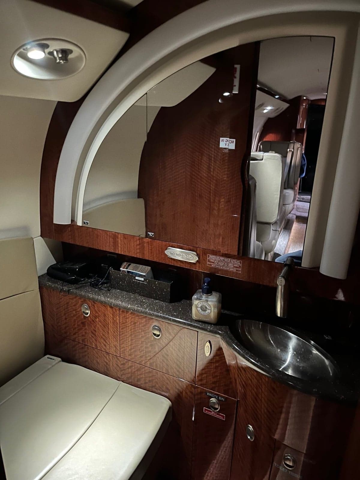 The aircraft's lavatory or galley area with a sink, mirror, and wood cabinetry.