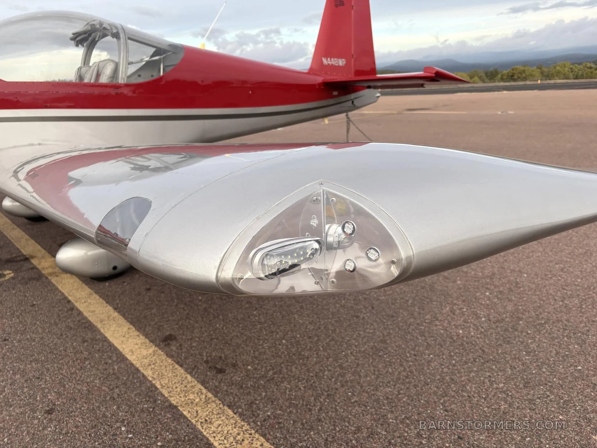 A close-up view of the silver wingtip of aircraft N448WP, showing the navigation and landing lights.