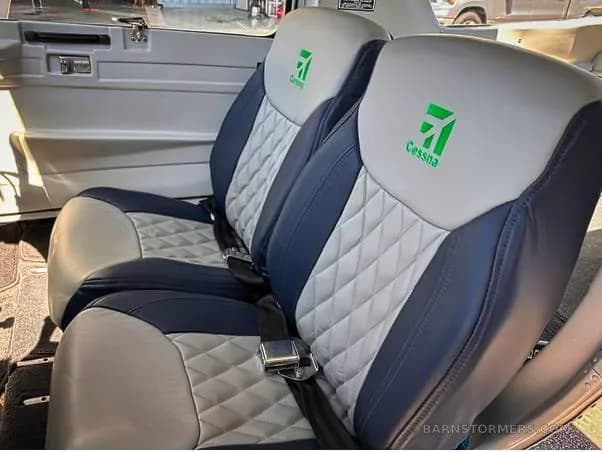 Two aircraft seats with blue and white quilted leather upholstery and green Cessna logos on the headrests.