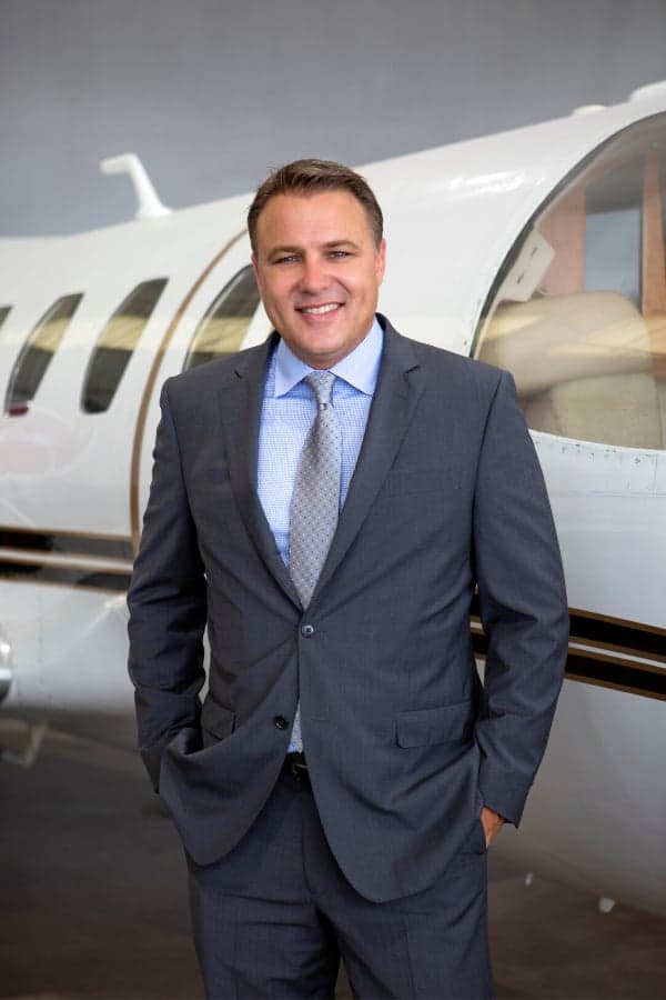 Man in a suit standing in front of the aircraft.