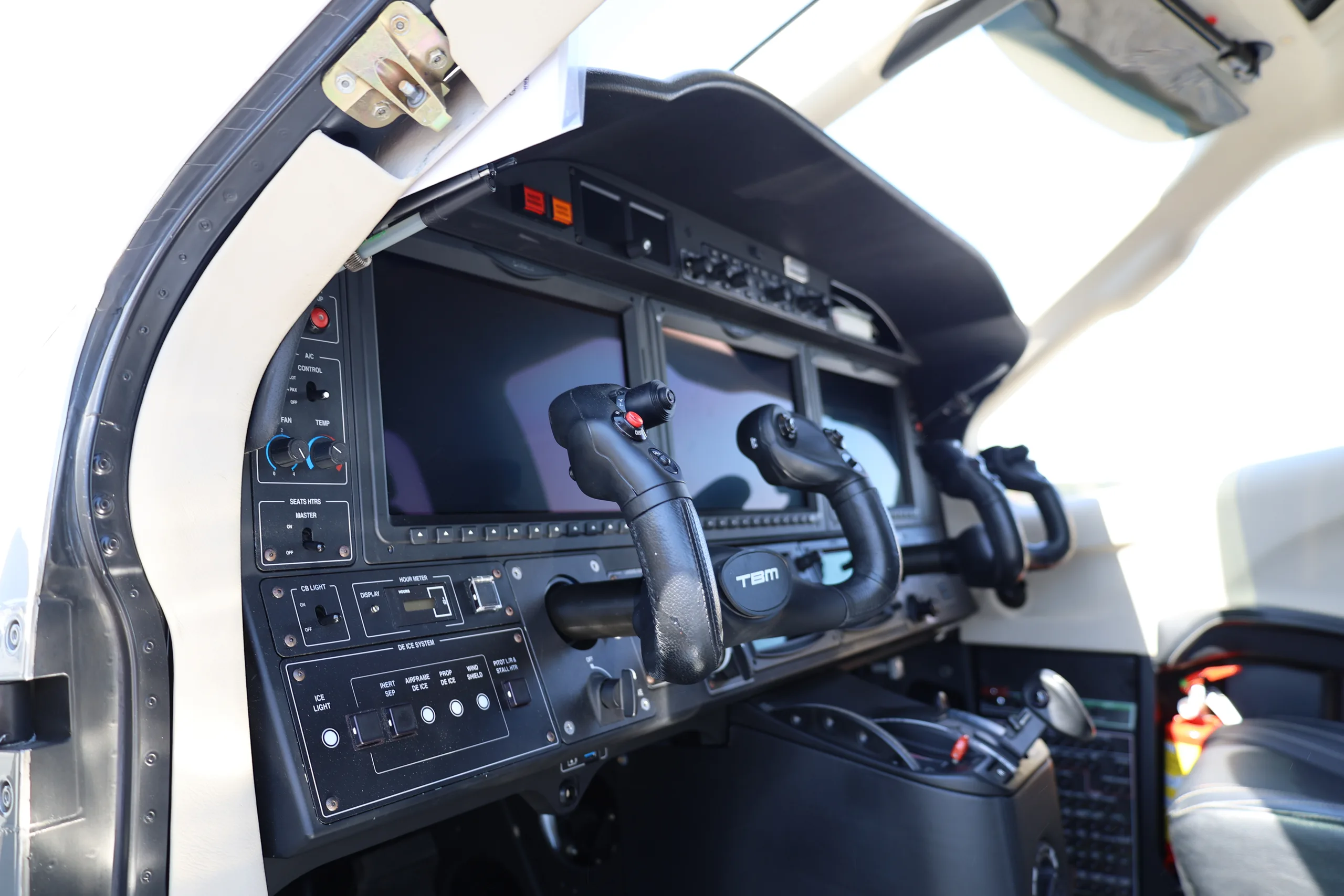 A close-up view of the TBM 940 cockpit instrument panel with multiple display screens and control yokes.