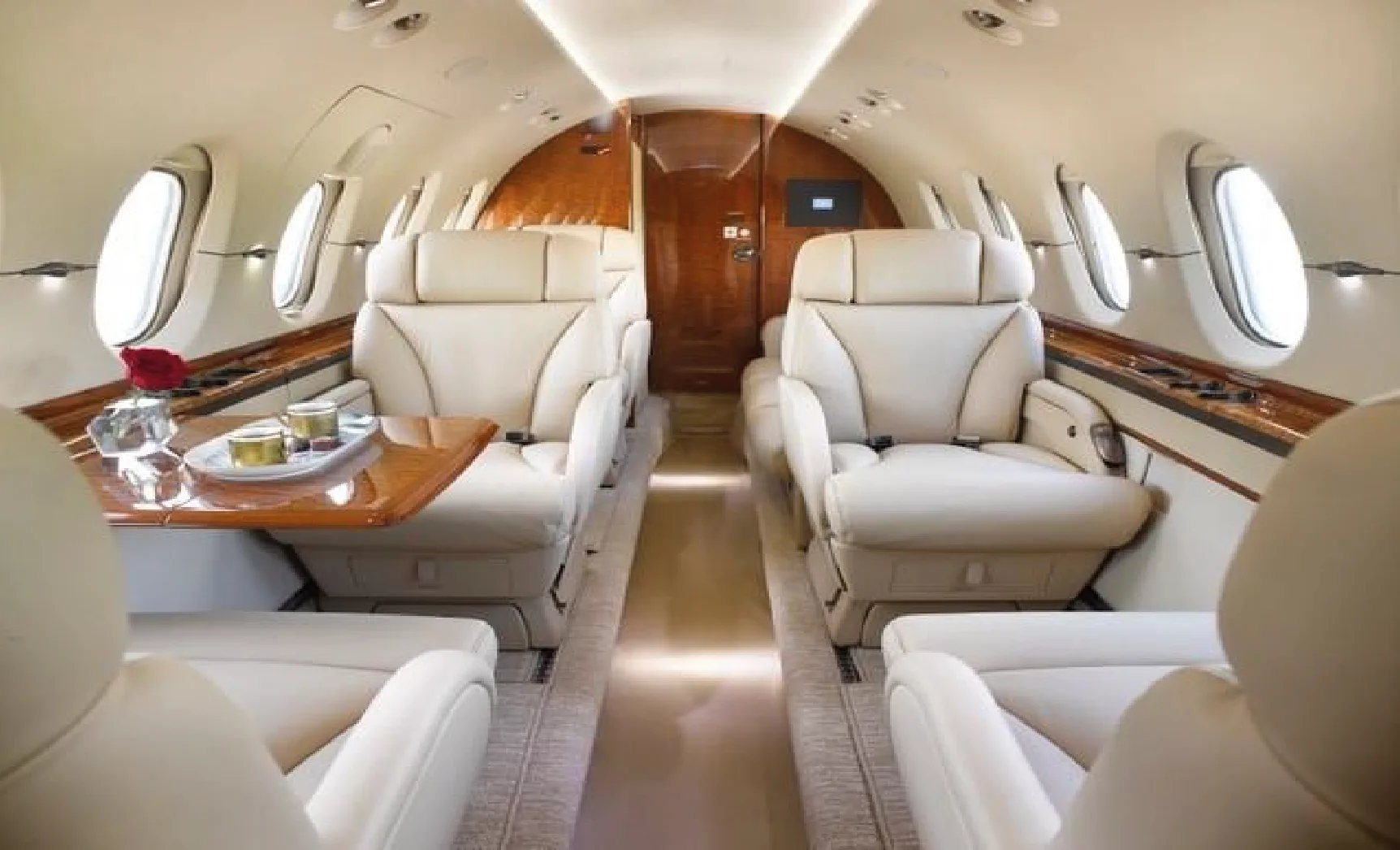 Aircraft interior with cream-colored leather seats and wood trim.