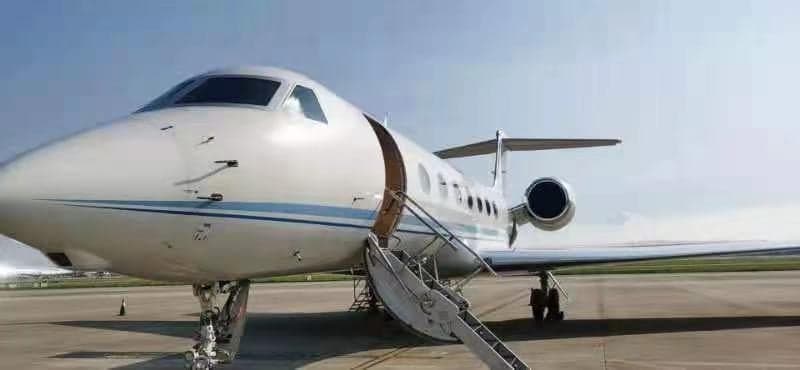 A Gulfstream G550 jet parked on the tarmac with the entry stairs down.