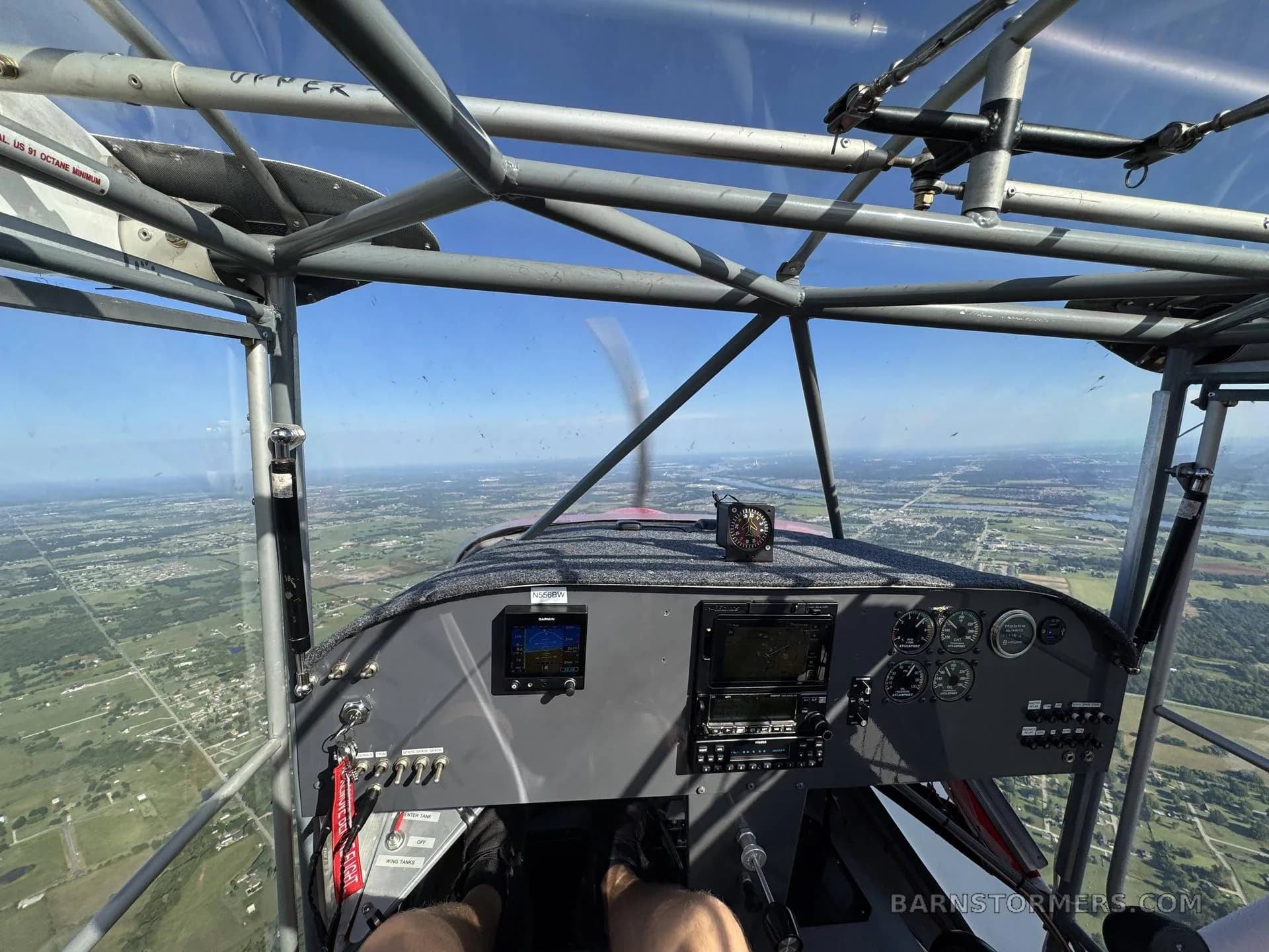 A pilot's view from the cockpit of a light sport aircraft, showing the instrument panel and a landscape below.