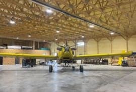 Front view of a yellow and blue agricultural aircraft parked in a hangar.