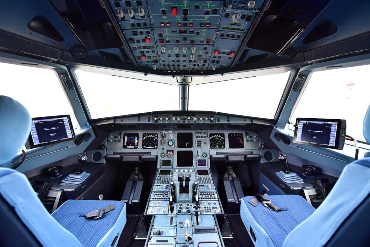The cockpit of an aircraft with blue seats and digital displays.