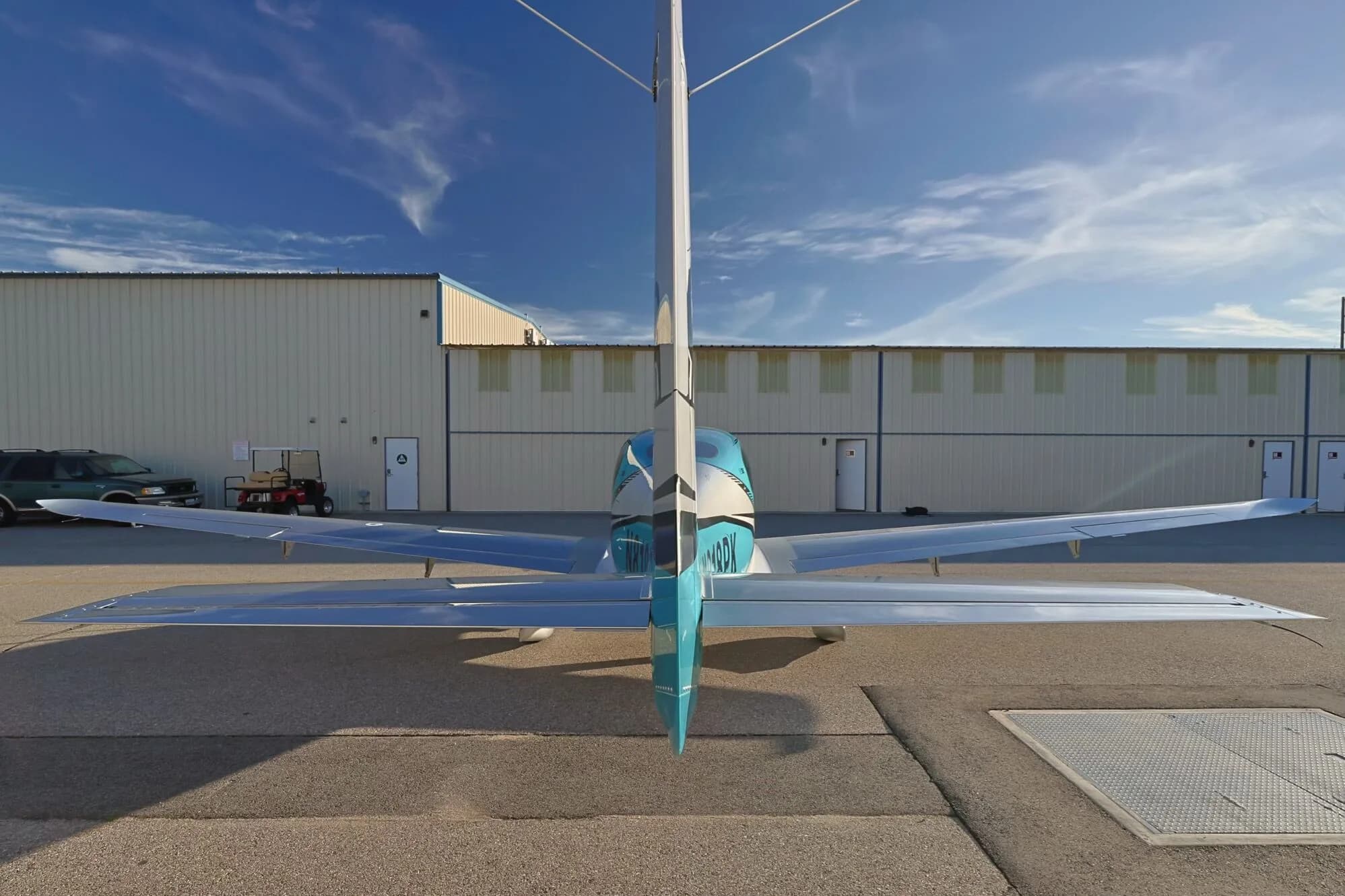 A rear view of a teal and silver Cirrus SR22T GTS aircraft (N818PK) parked on an airfield.
