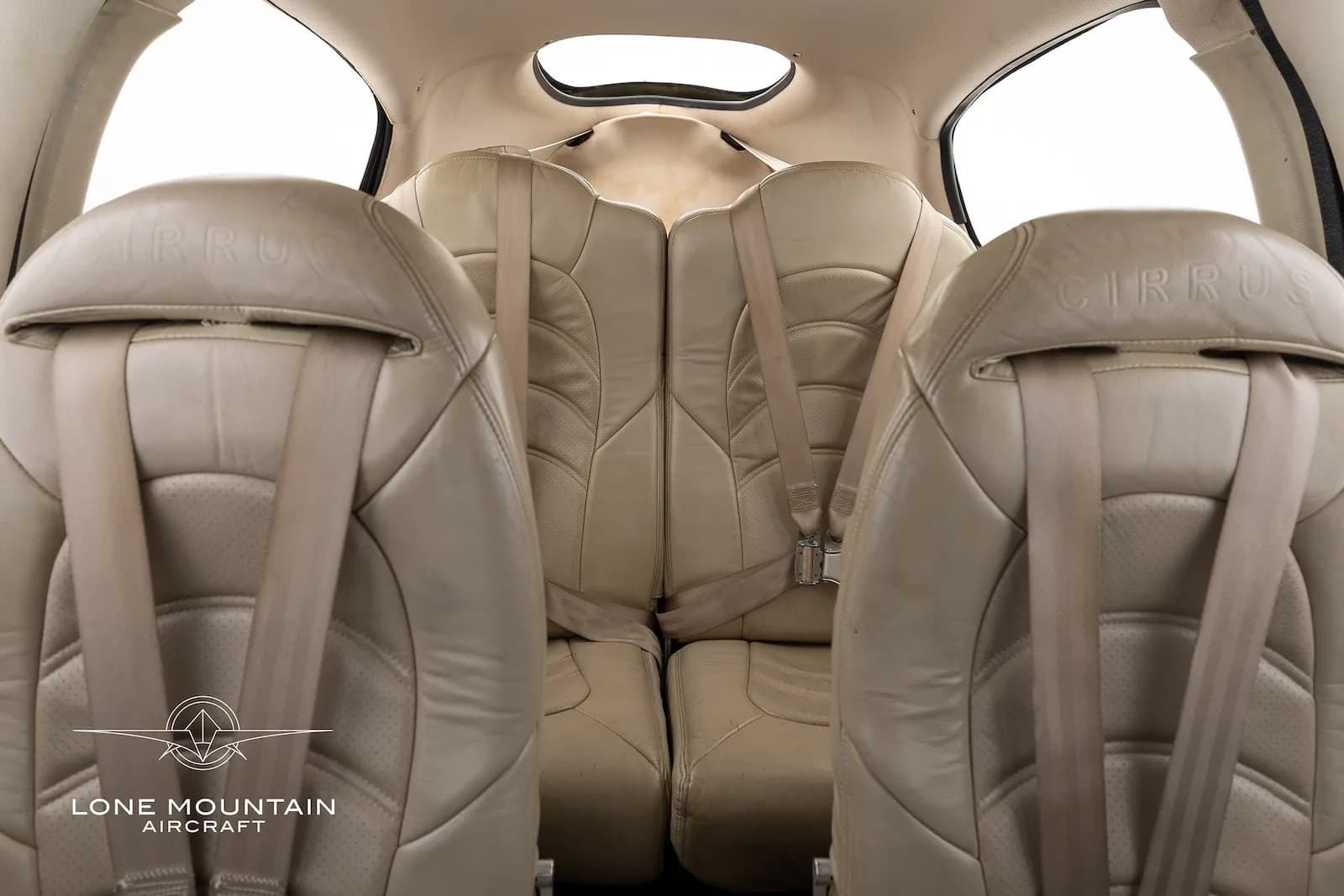 The beige leather rear seats of a Cirrus SR22 aircraft cabin, with seatbelts visible.