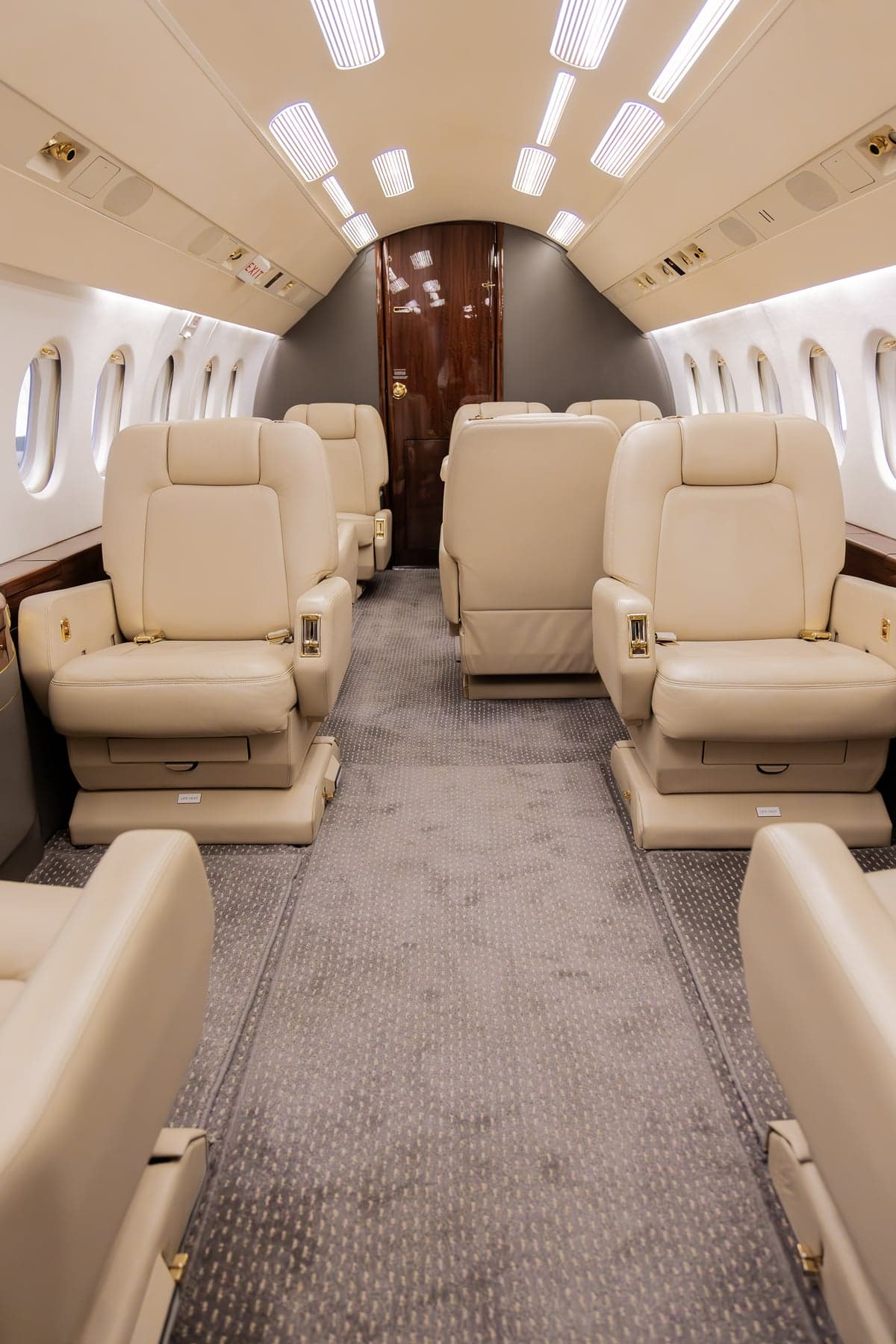 A view of the aircraft's interior, featuring beige leather seats and a central aisle.