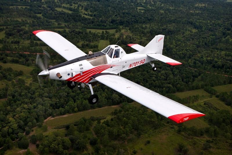 Air Tractor 710P in flight over a wooded area.