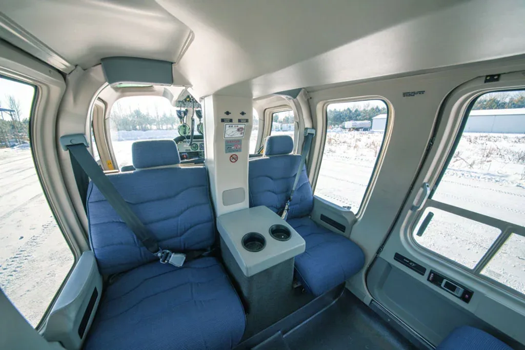 The helicopter's cabin interior with blue seats and a center console, looking towards the cockpit.
