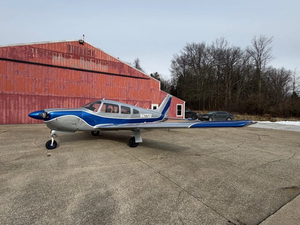 A Piper PA-28-181 Archer II aircraft with registration N47723 parked on the tarmac in front of a hangar.
