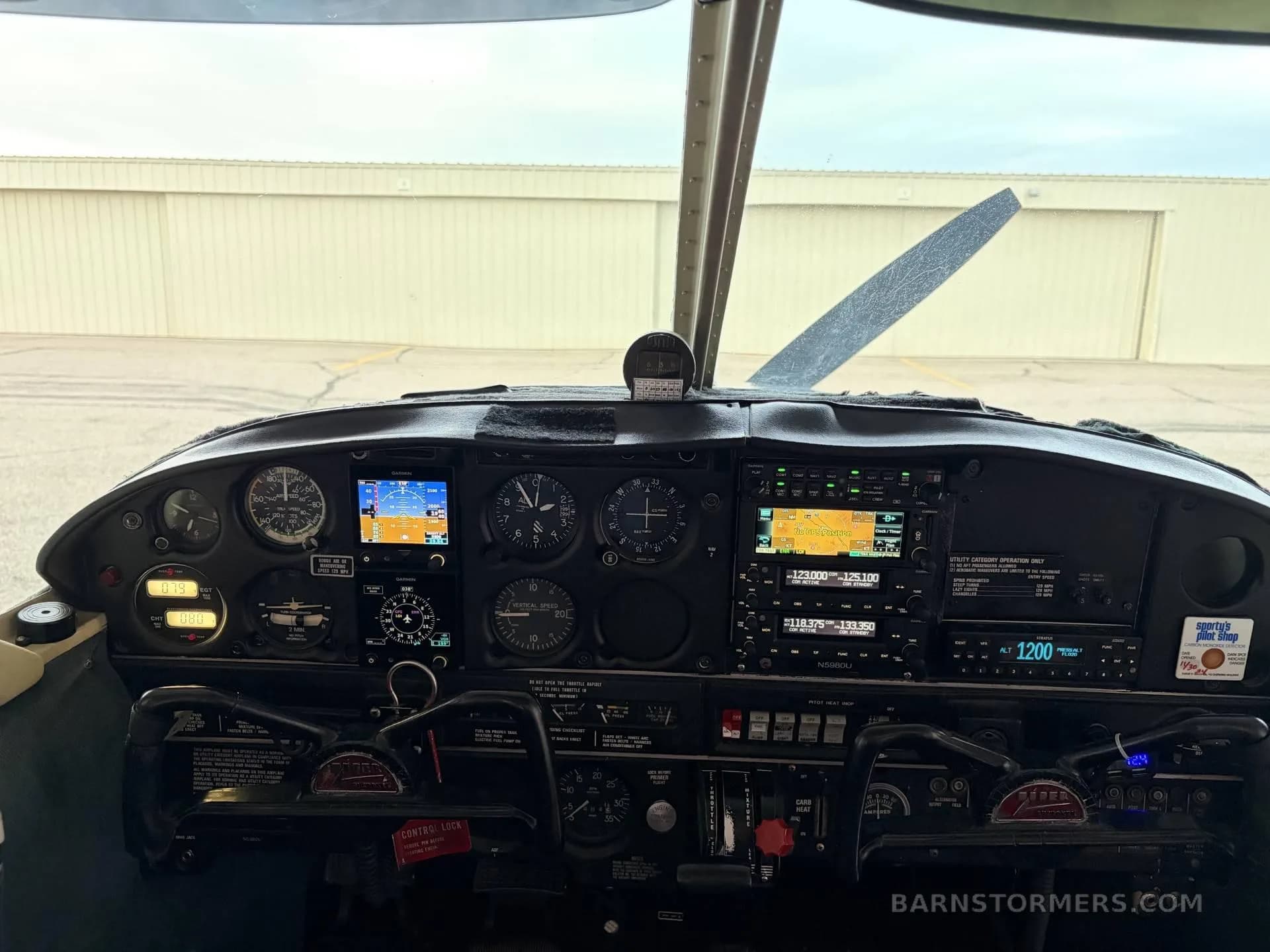 The cockpit instrument panel of a single-engine aircraft, showing analog gauges and two digital displays.