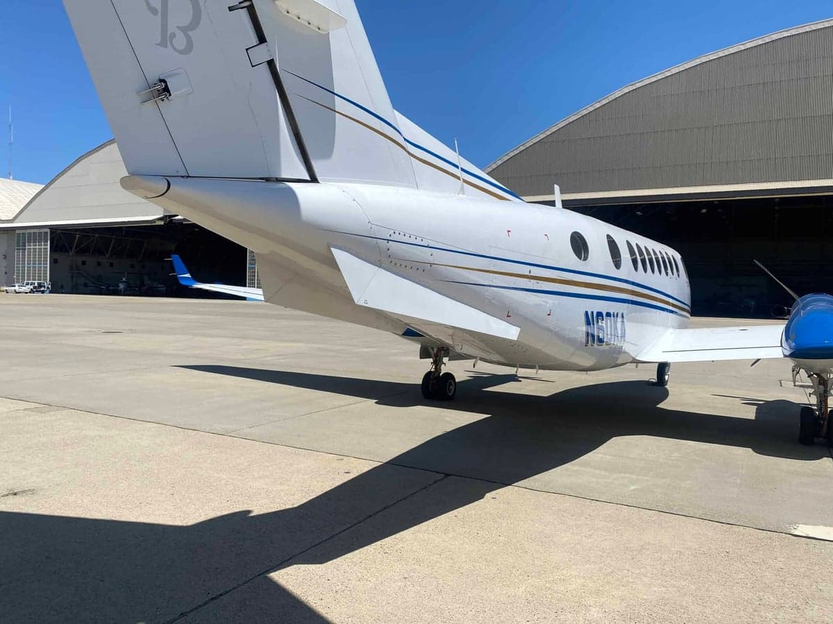 A rear-quarter view of the white and blue Beechcraft King Air 350 with registration N60KA parked on the tarmac.