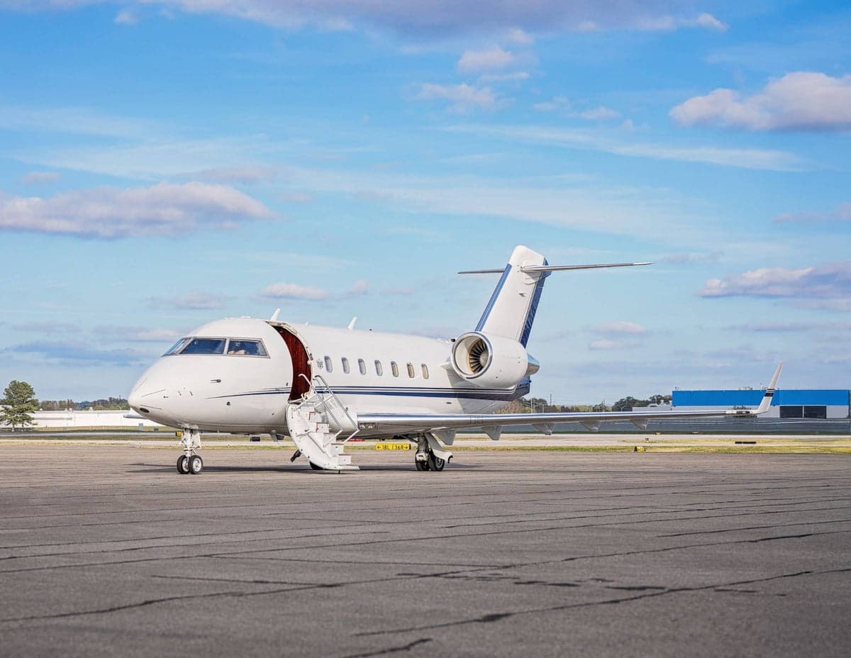 A Challenger aircraft is parked on the tarmac with the stairs down.