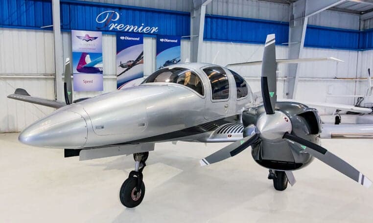 Front view of a Diamond DA62 aircraft with a silver and gray paint scheme in a hangar.
