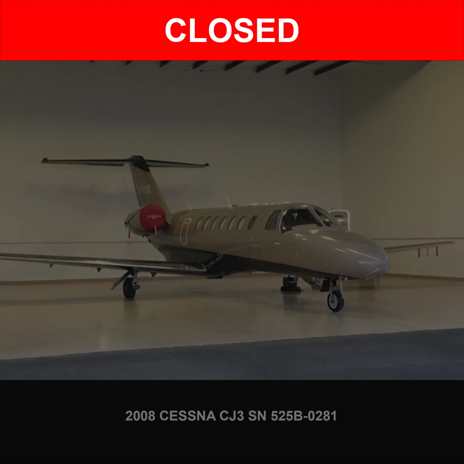 A tan and dark-accented Cessna CJ3 business jet is parked inside a hangar.