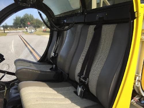 The interior of the helicopter shows gray and black seats with seatbelts.