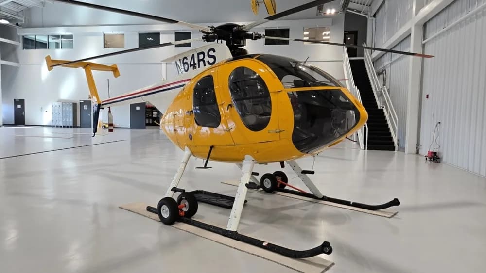 A front-right view of the yellow N64RS helicopter on skids in a hangar.