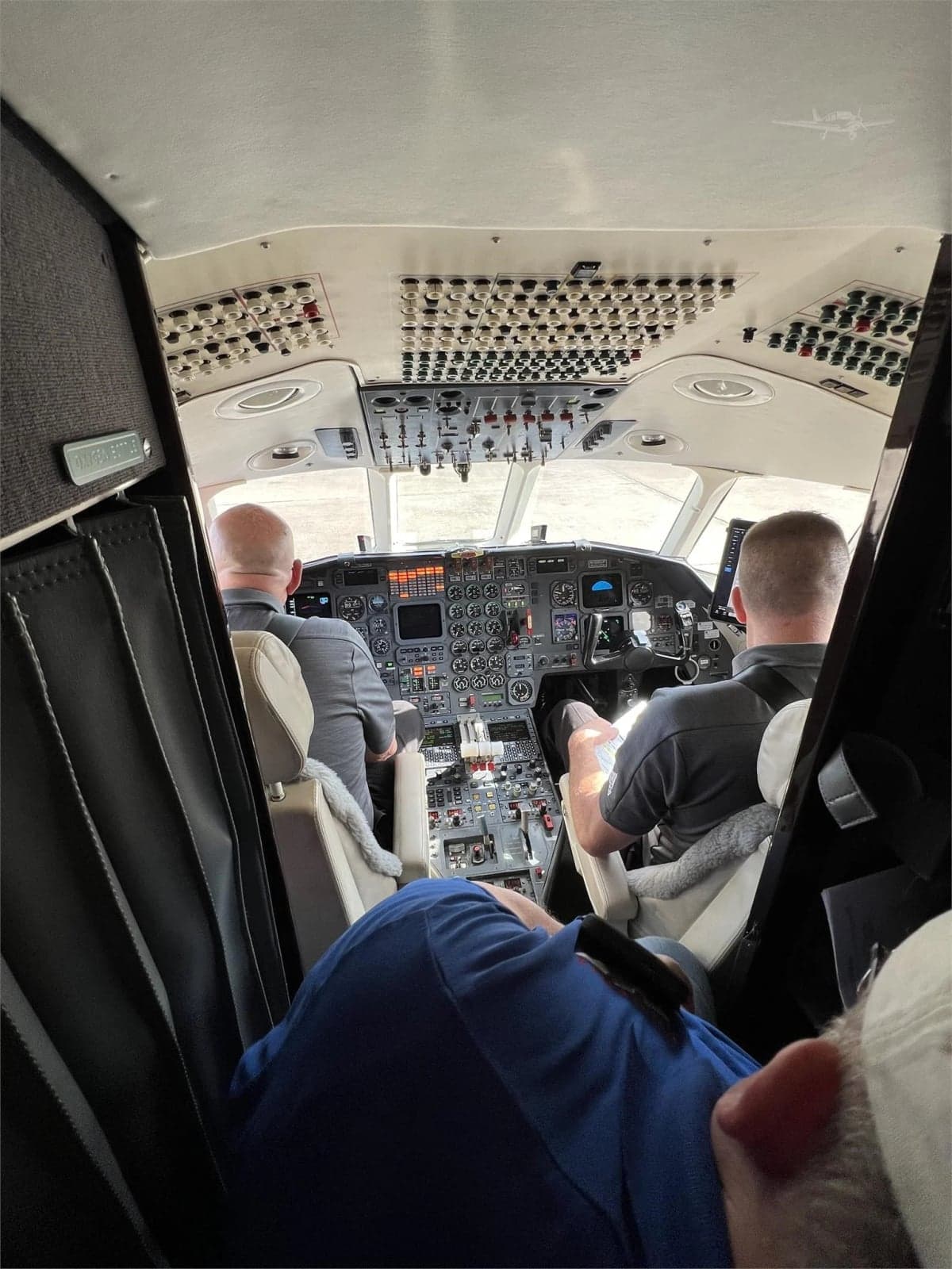 Interior view of the aircraft cabin with cream-colored leather seats and a small television screen.