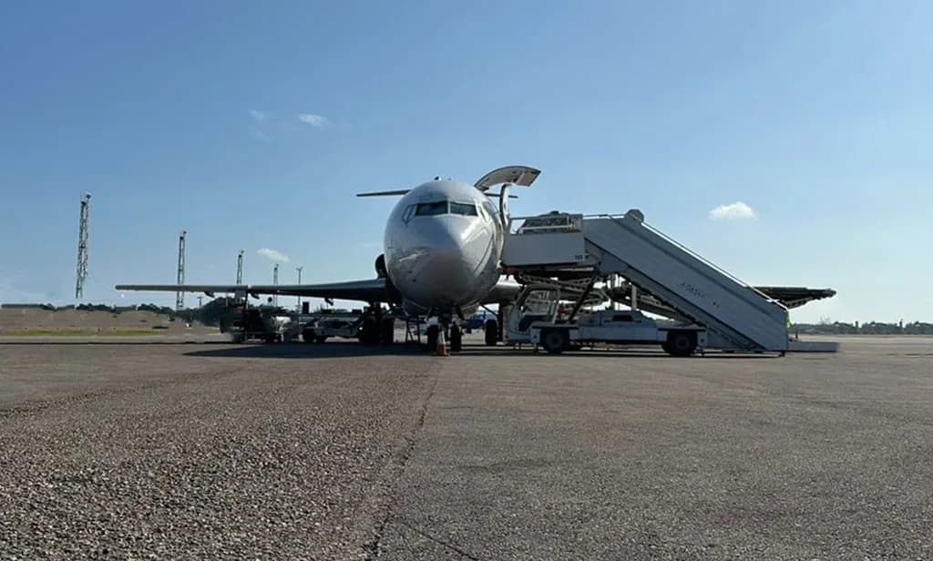 A front view of a UniWorld Air Cargo Boeing 727-200F parked on the tarmac with mobile stairs.