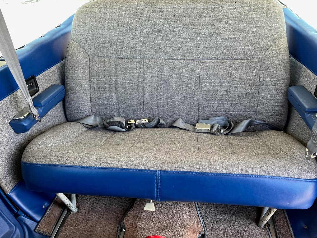 Rear bench seat in the cabin of the Cessna Cardinal RG, upholstered in gray fabric with blue trim.