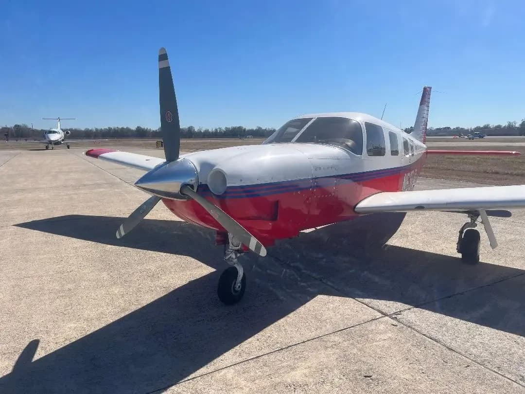 A red and white single-engine propeller aircraft, N3258H, parked on an airfield on a clear day.