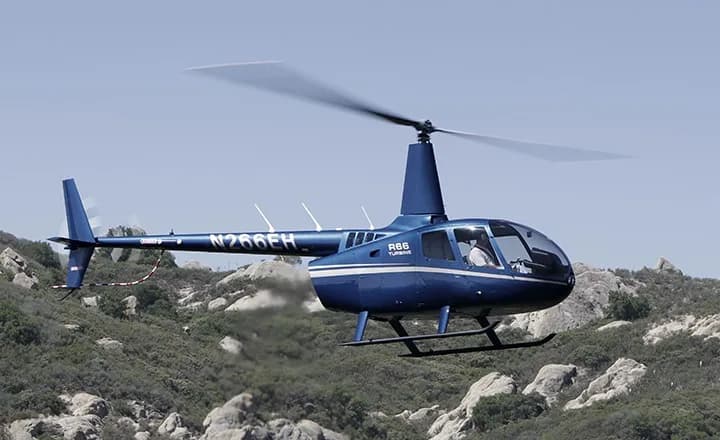 A blue Robinson R66 Turbine helicopter in flight.