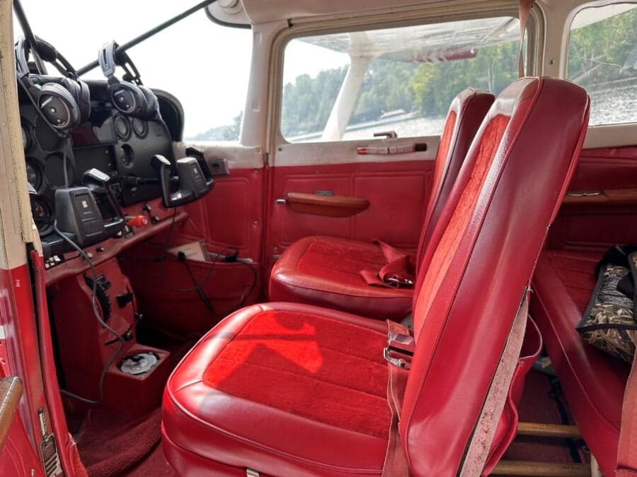 The interior of the Cessna floatplane features red seats and a view of the cockpit.