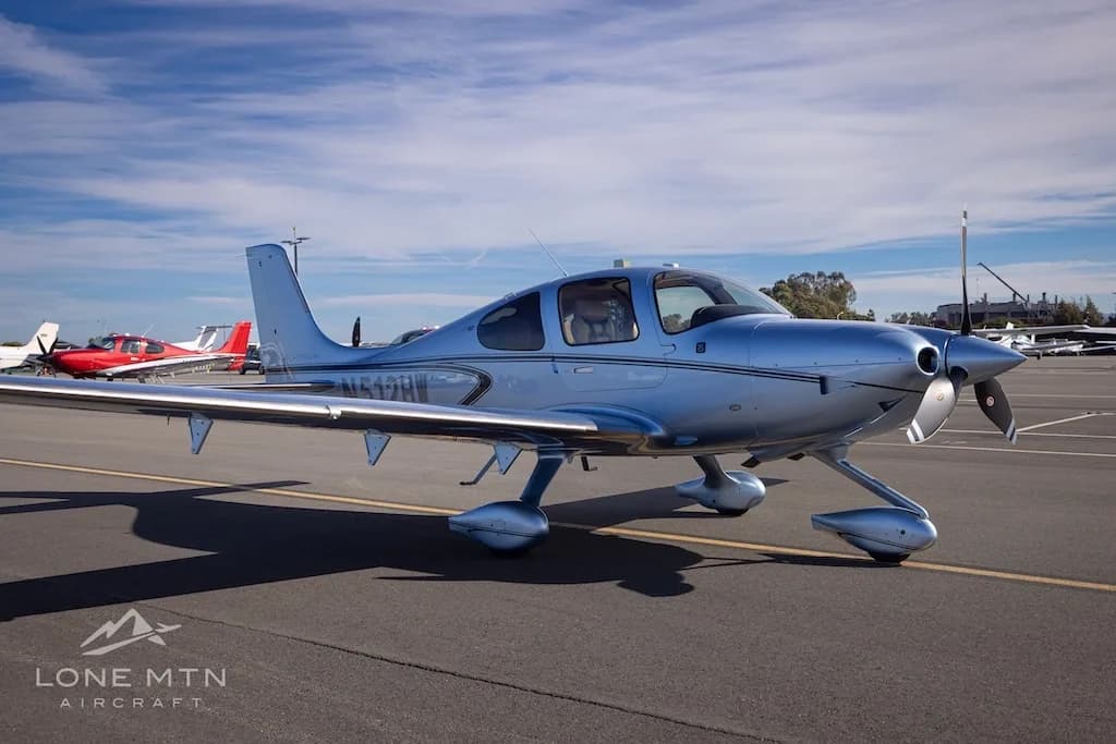 Front-right view of a silver Cirrus SR22 aircraft, N512HW, parked on an airfield.