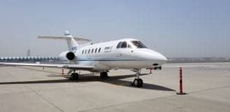 A white aircraft is parked on the tarmac on a sunny day.